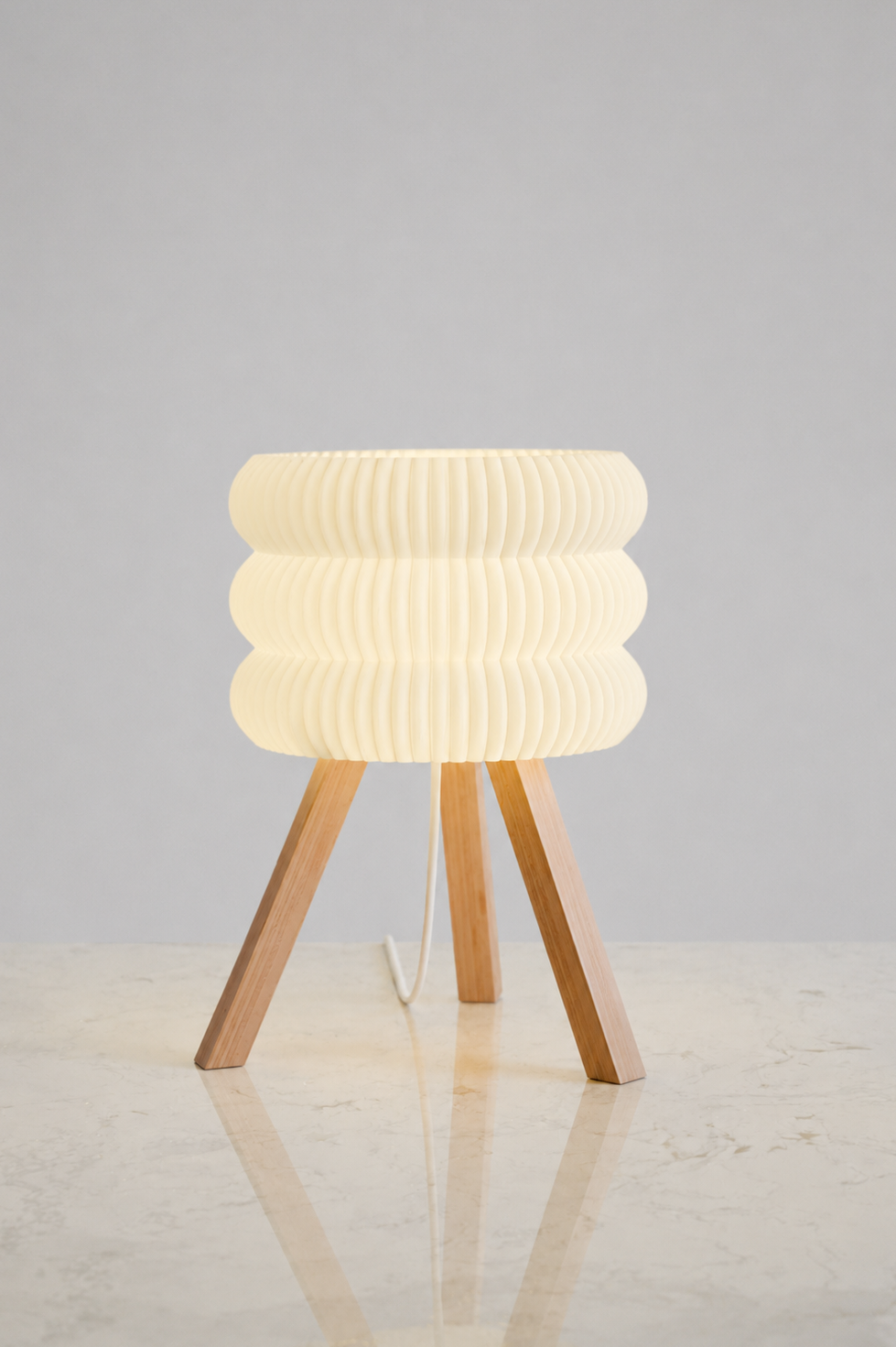 Modern table lamp with ribbed design and wooden legs on a light gray background